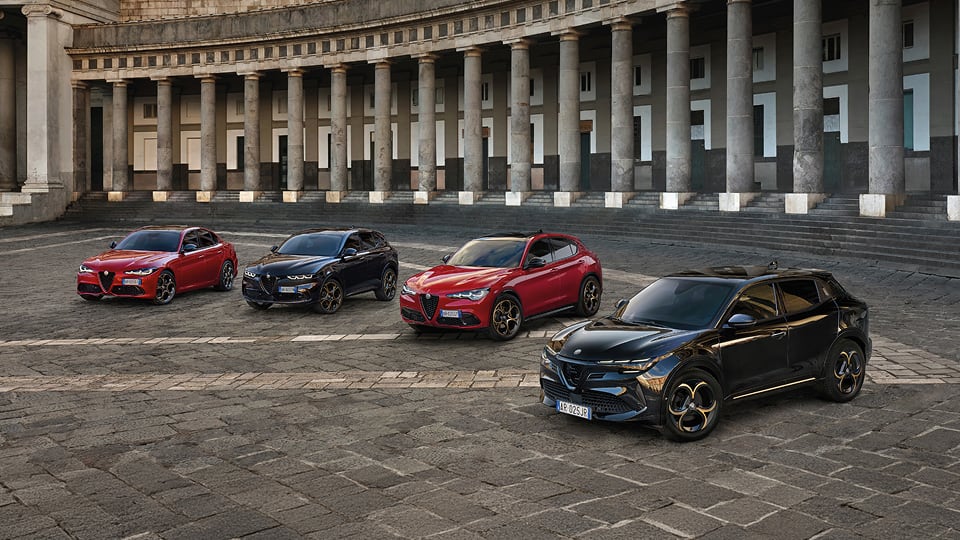 Front angled view of multiple Alfa Romeo vehicles parked in a semi circle on a stone plaza