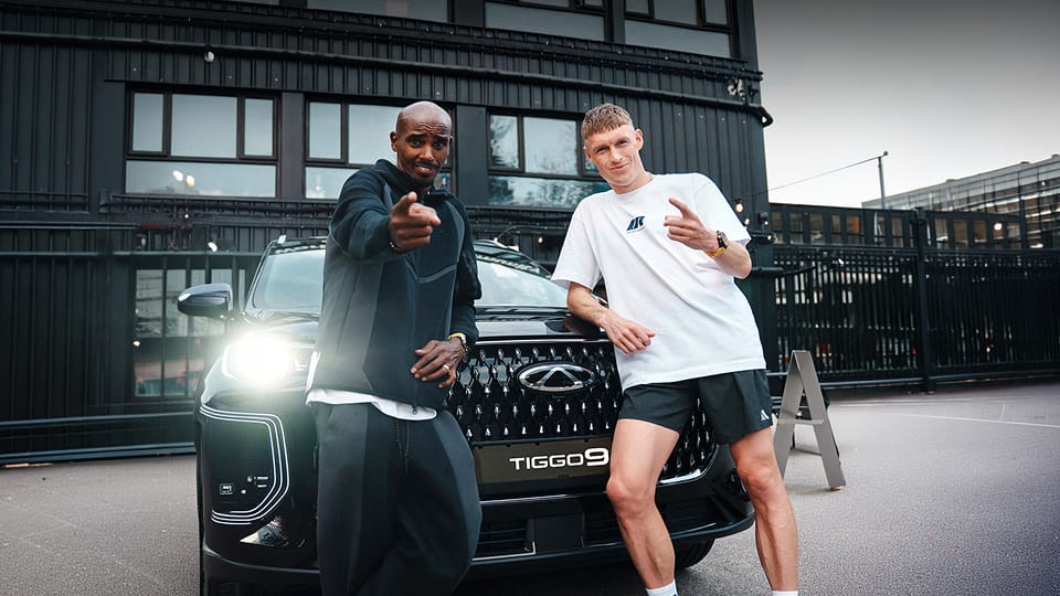 Mo Farah and Adam Clarke standing infront of a Chery Tiggo 9 with it's lights on