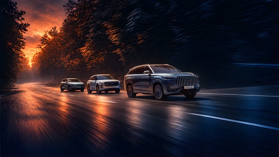 OMODA and JAECOO cars travelling along country road at night with orange glow in sky