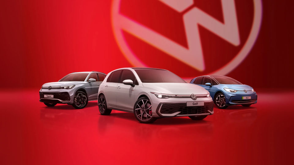 Range of Volkswagens against a red background with the Volkswagen badge in the distance